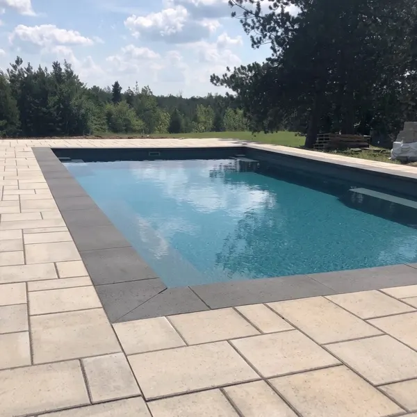 Rectangle inground pool with a natural stone slab surround and charcoal coping, pool landscaping Guelph